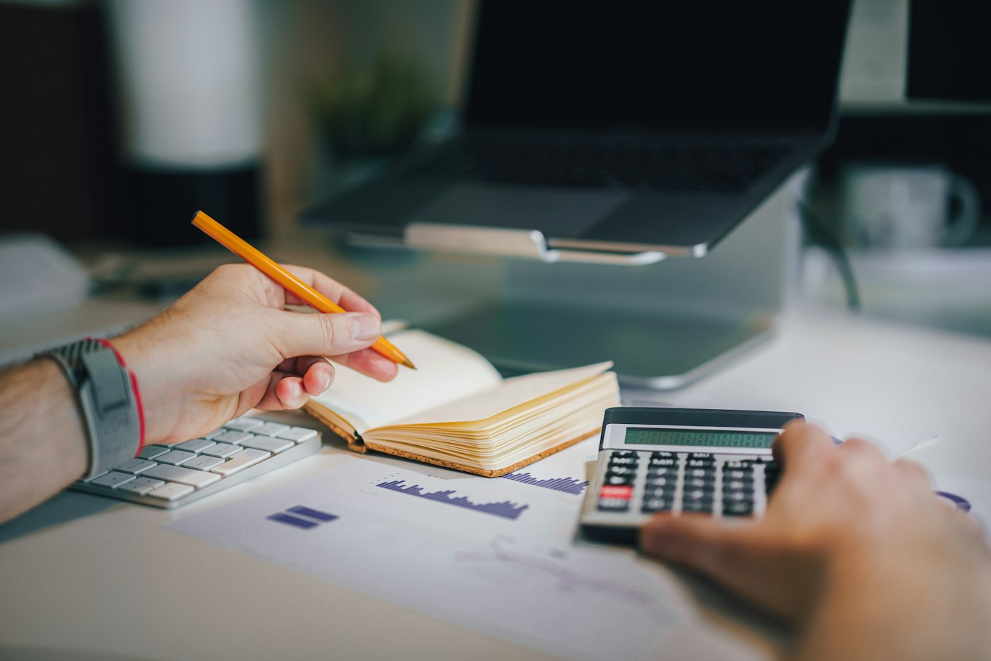 Working through figures with a pencil, calculator, notebook and printed financial report